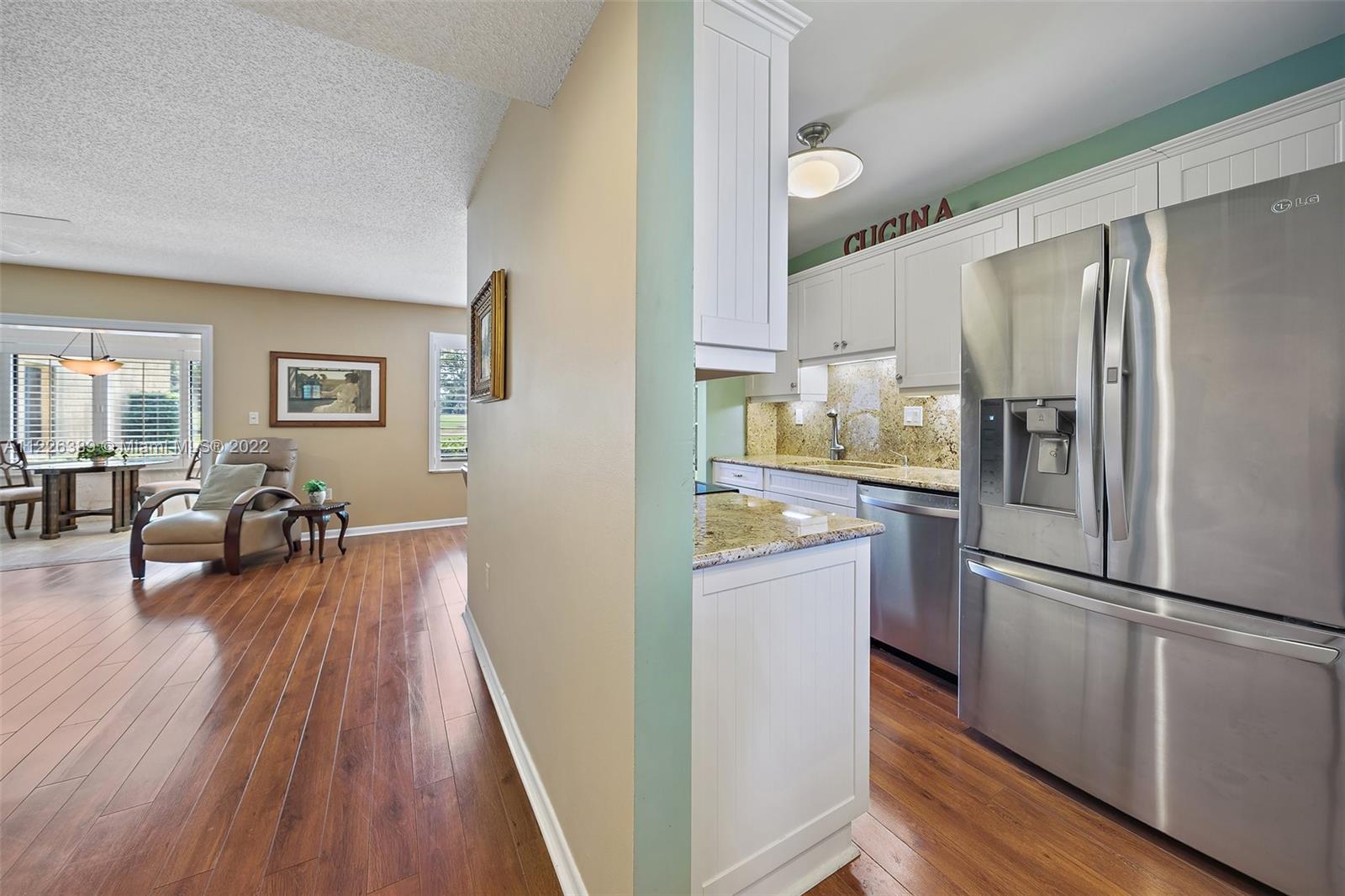 5335 Southeast Miles Grant Road, Unit 107 Stuart, FL 34997 - Photo 6 of 44 a kitchen with stainless steel appliances a refrigerator a stove a dining table and chairs with wooden floor