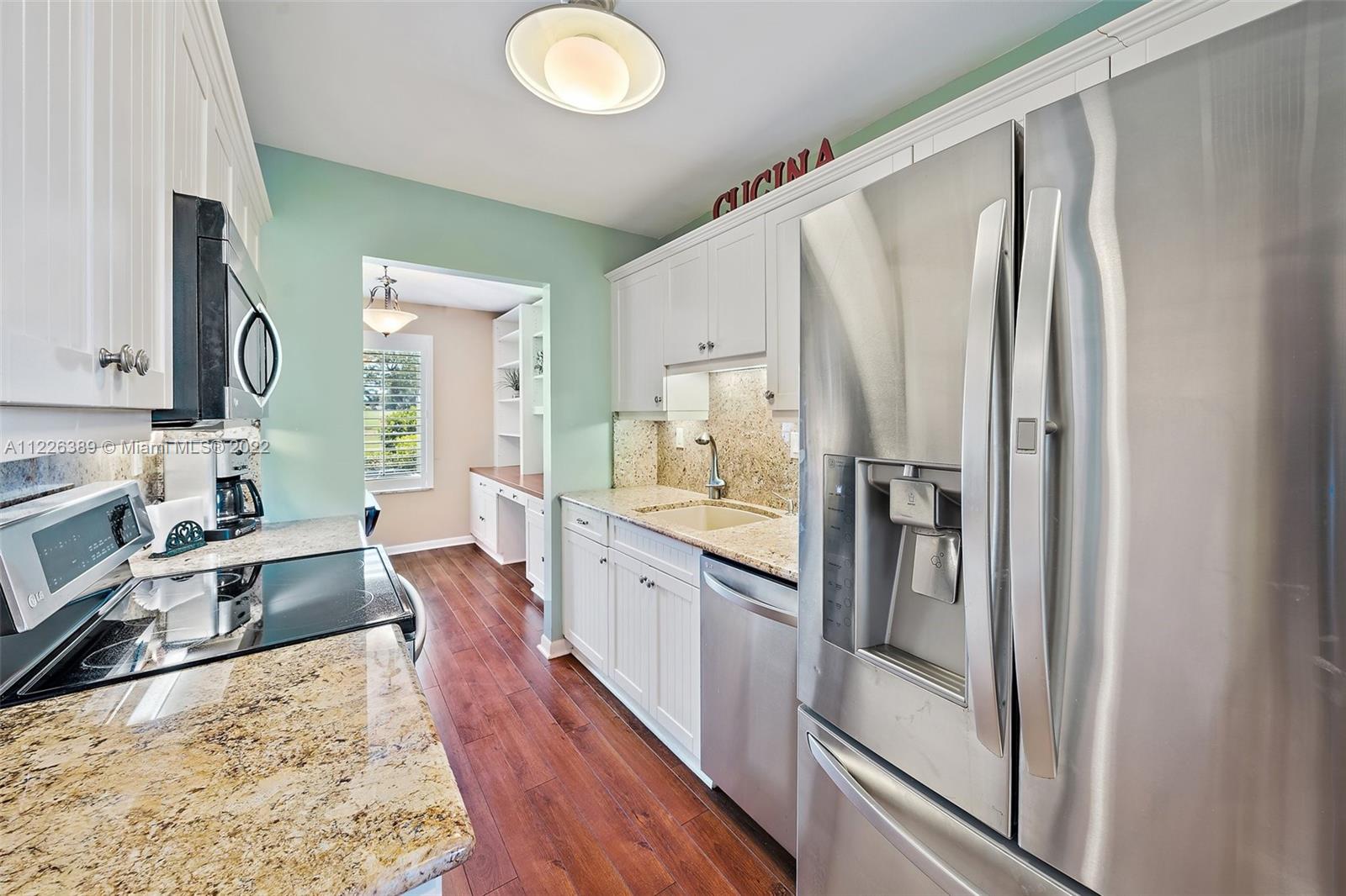 5335 Southeast Miles Grant Road, Unit 107 Stuart, FL 34997 - Photo 8 of 44 a large kitchen with kitchen island a large counter space a sink appliances and cabinets
