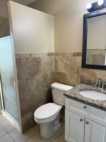 a bathroom with a granite countertop toilet a sink and a mirror
