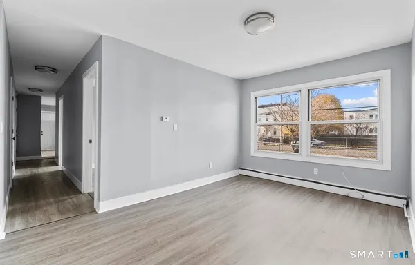 a view of an empty room with a window and wooden floor