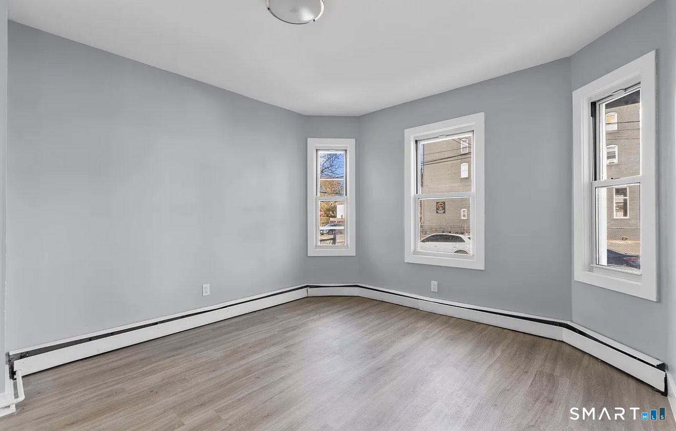 746 Maple Street Bridgeport, CT 06608 - Photo 7 of 12 an empty room with wooden floor and windows