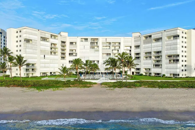 a front view of a building with a garden and trees