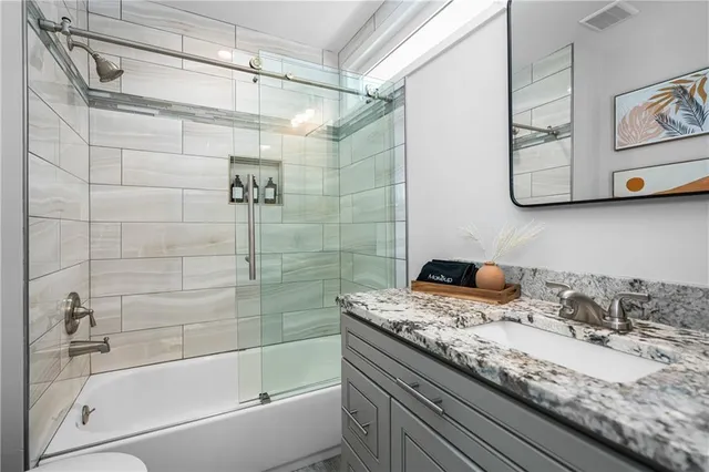 a bathroom with a granite countertop sink a mirror and shower