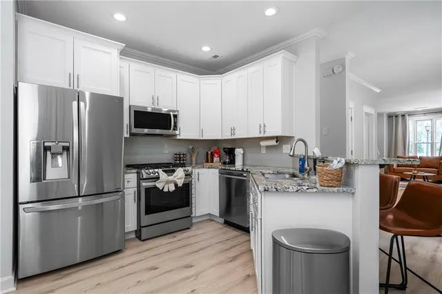 a kitchen with stainless steel appliances a refrigerator a stove a sink cabinets and a wooden floor