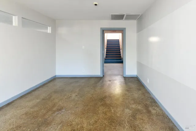 an empty room with wooden floor a chandelier and windows