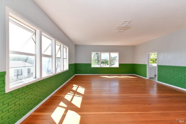 a view of an empty room with wooden floor and window