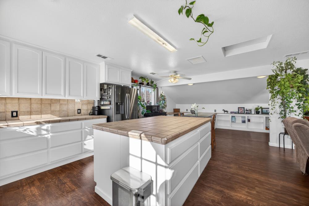 13512 Alta Mesa Road Galt, CA 95632 - Photo 33 of 99 a kitchen with a stove a refrigerator and a dining table with wooden floor