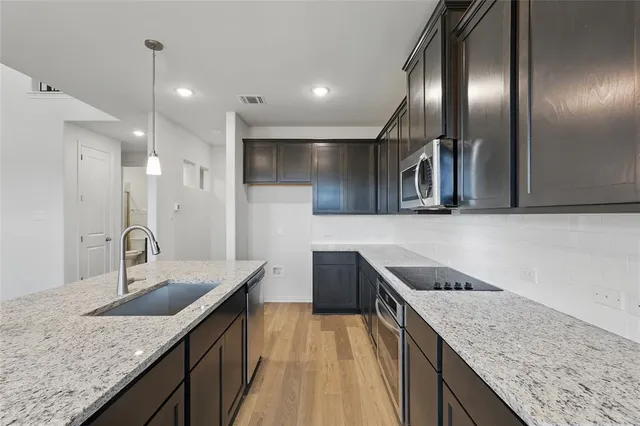 a kitchen with granite countertop kitchen island a sink appliances and a counter space