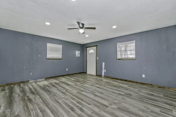 an empty room with wooden floor and windows