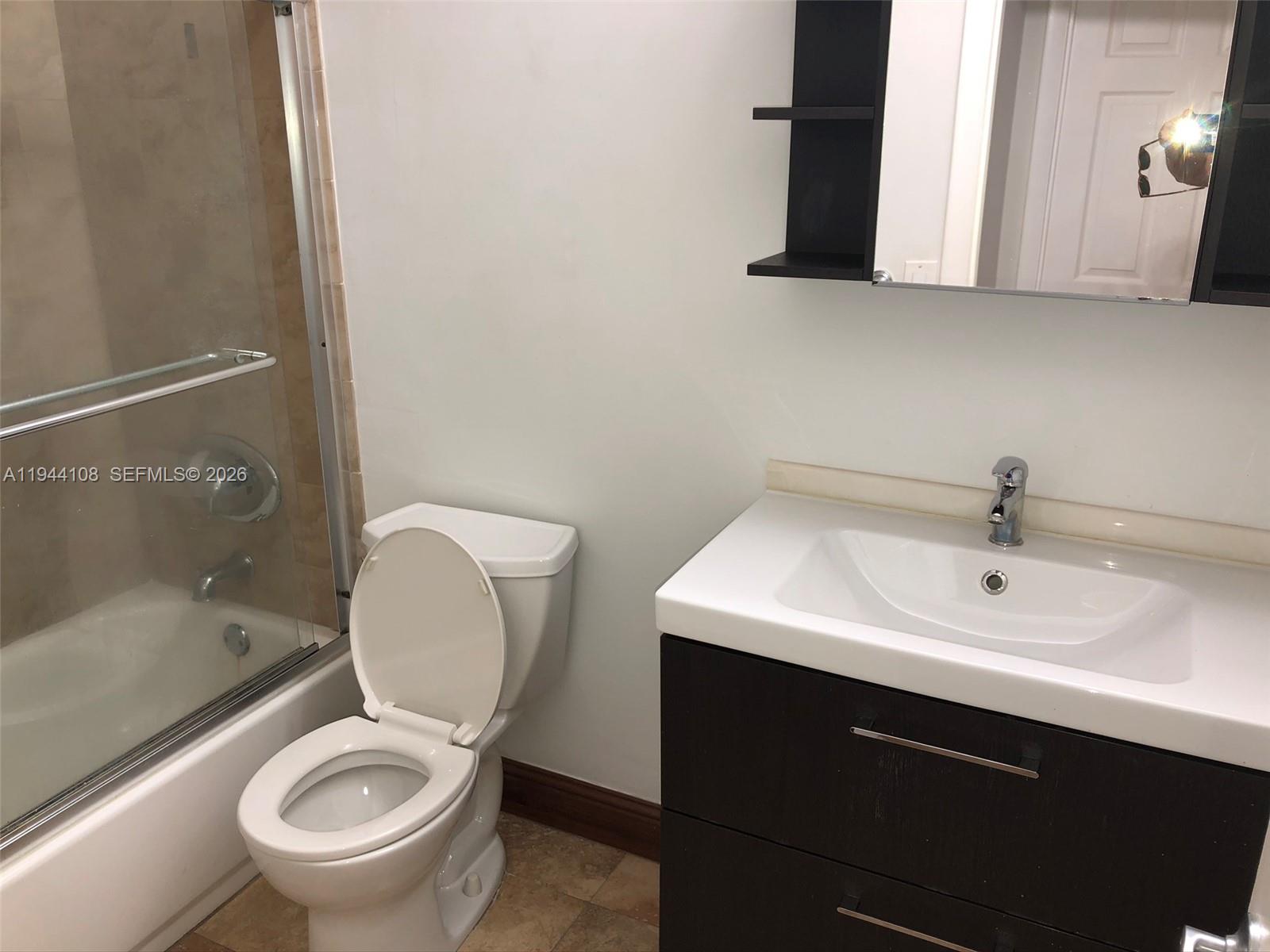 10794 North Kendall Drive, Unit B14 Miami, FL 33176 - Photo 4 of 23 a bathroom with a sink a toilet and a mirror
