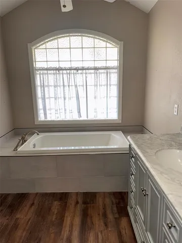a bathroom with a granite countertop bathtub and next to a window