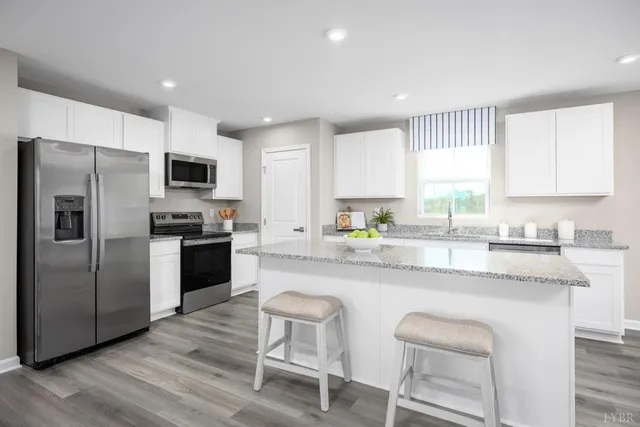 a kitchen with kitchen island granite countertop a sink cabinets stainless steel appliances and a window