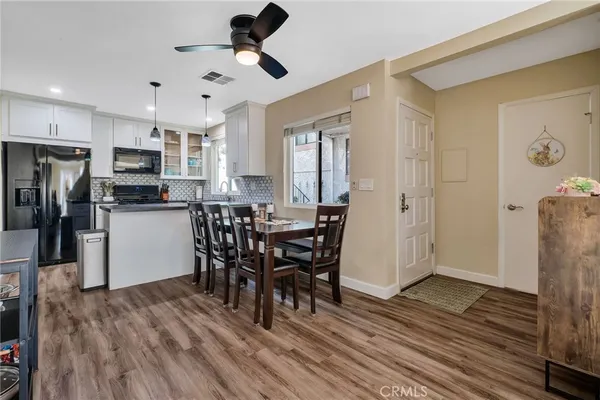 a kitchen with stainless steel appliances a dining table chairs refrigerator and microwave