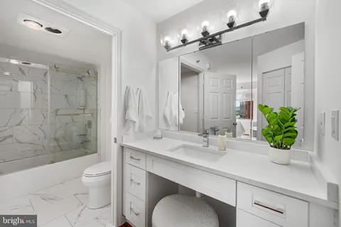 a bathroom with a granite countertop sink a toilet a mirror and shower