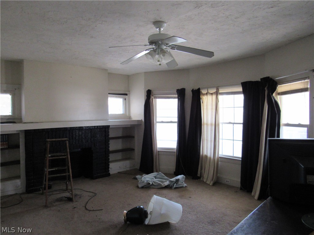 863 Eddy Road Cleveland, OH 44108 - Photo 13 of 28 Room featuring a ceiling fan, multiple windows, built-in shelving, and a dark-toned fireplace with a mantel. Unit 2
