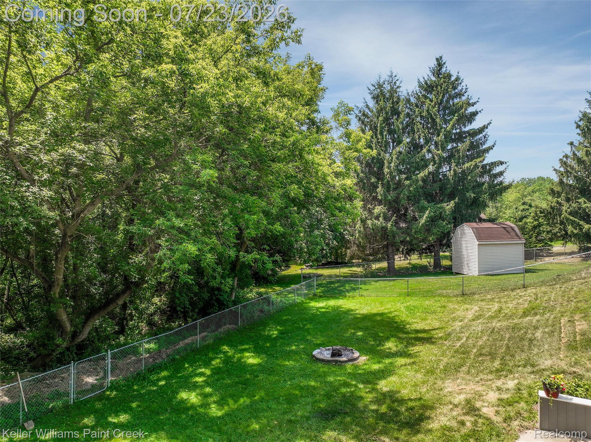 2611 Quail Run Street Rochester, MI 48306 - Photo 48 of 48 Expansive rear yard featuring a chain-link fence, mature trees, a storage shed, and a circular fire pit