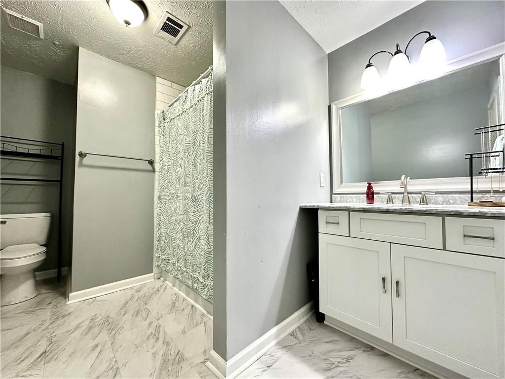 766 Country Club Road Newnan, GA 30263 - Photo 27 of 34 Full bath featuring light marble finish flooring, vanity, a textured ceiling, and curtained shower