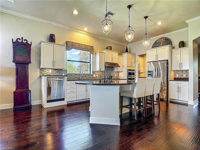 a kitchen with stainless steel appliances granite countertop a stove a refrigerator a sink dishwasher and a dining table with wooden floor