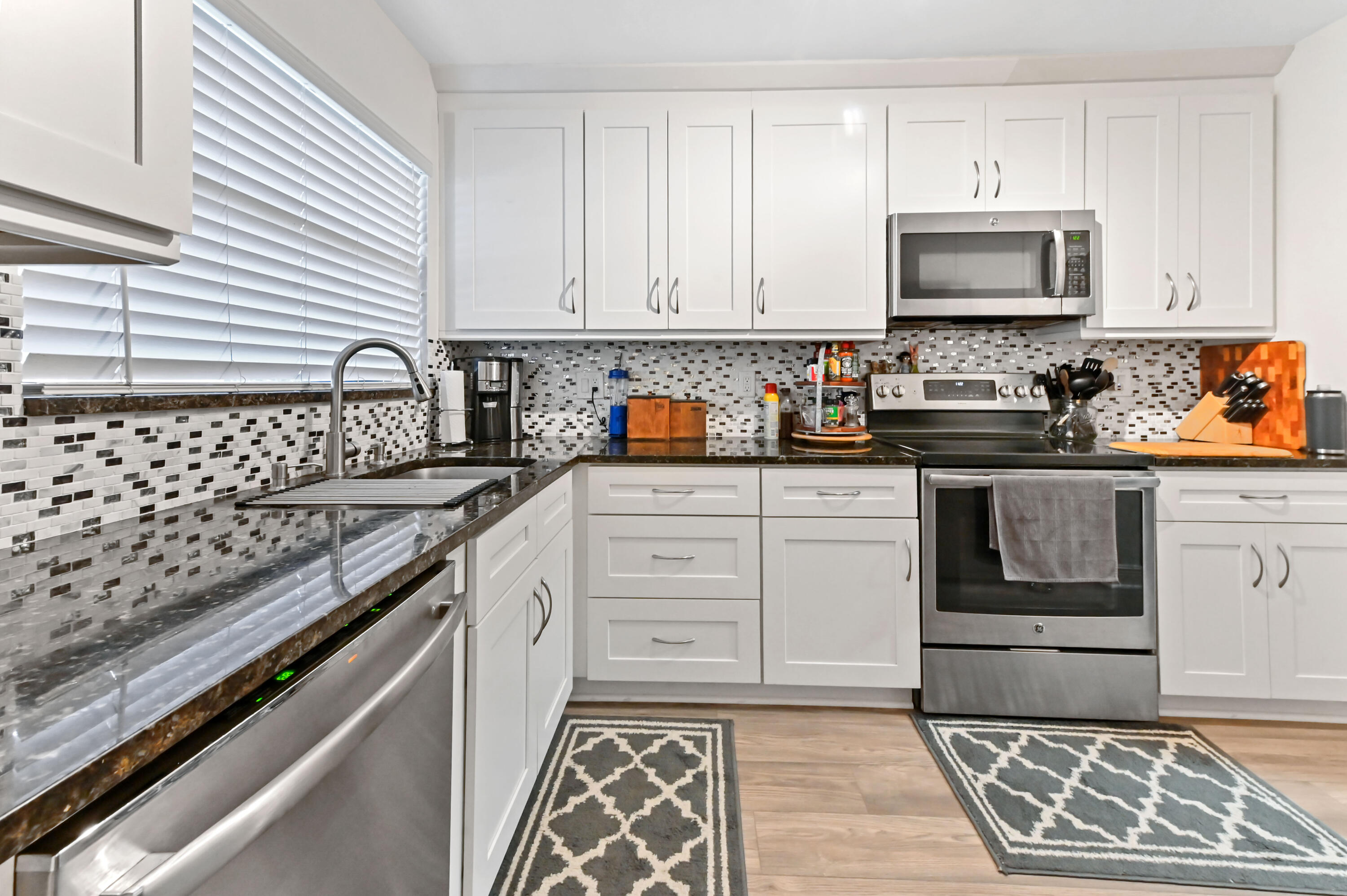 1230 Southeast Parkview Place, Unit D2 Stuart, FL 34994 - Photo 10 of 34 a kitchen with stainless steel appliances granite countertop a stove a sink and a microwave