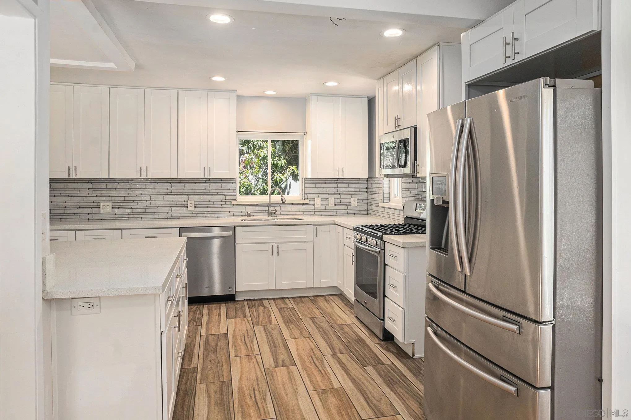 74 E Street Chula Vista, CA 91910 - Photo 38 of 56 a kitchen with a refrigerator a sink and white cabinets