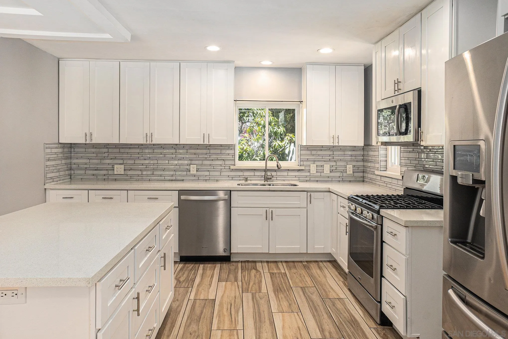 74 E Street Chula Vista, CA 91910 - Photo 39 of 56 a kitchen with a sink stove a refrigerator and white cabinets