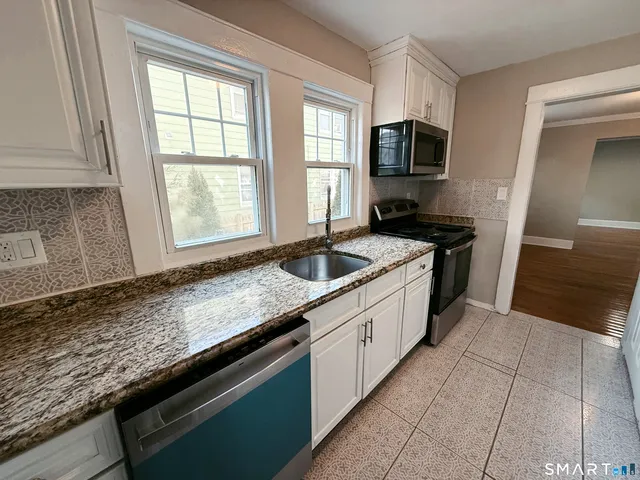 a kitchen with granite countertop stainless steel appliances a sink stove top oven and granite counter tops