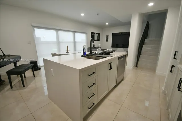 a kitchen with white cabinets a sink stove and a refrigerator