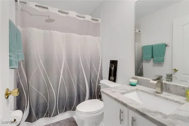 a bathroom with a granite countertop sink toilet and a mirror