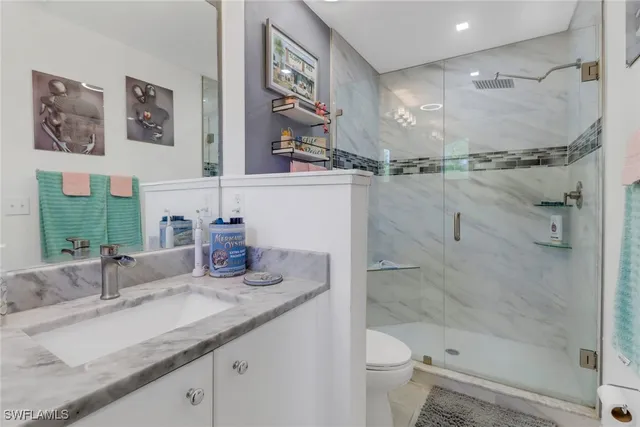 a bathroom with a granite countertop sink mirror vanity and toilet