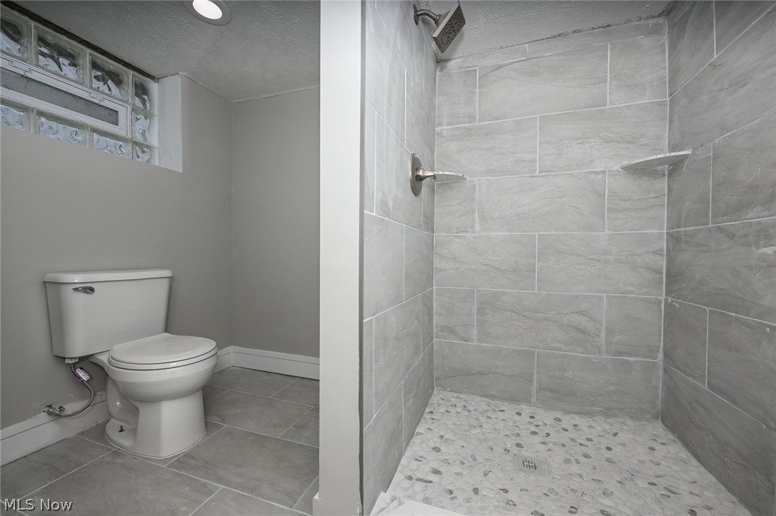 1520 Sheffield Road Cleveland, OH 44121 - Photo 34 of 36 Bathroom with tile floors, tiled shower, toilet, and a textured ceiling