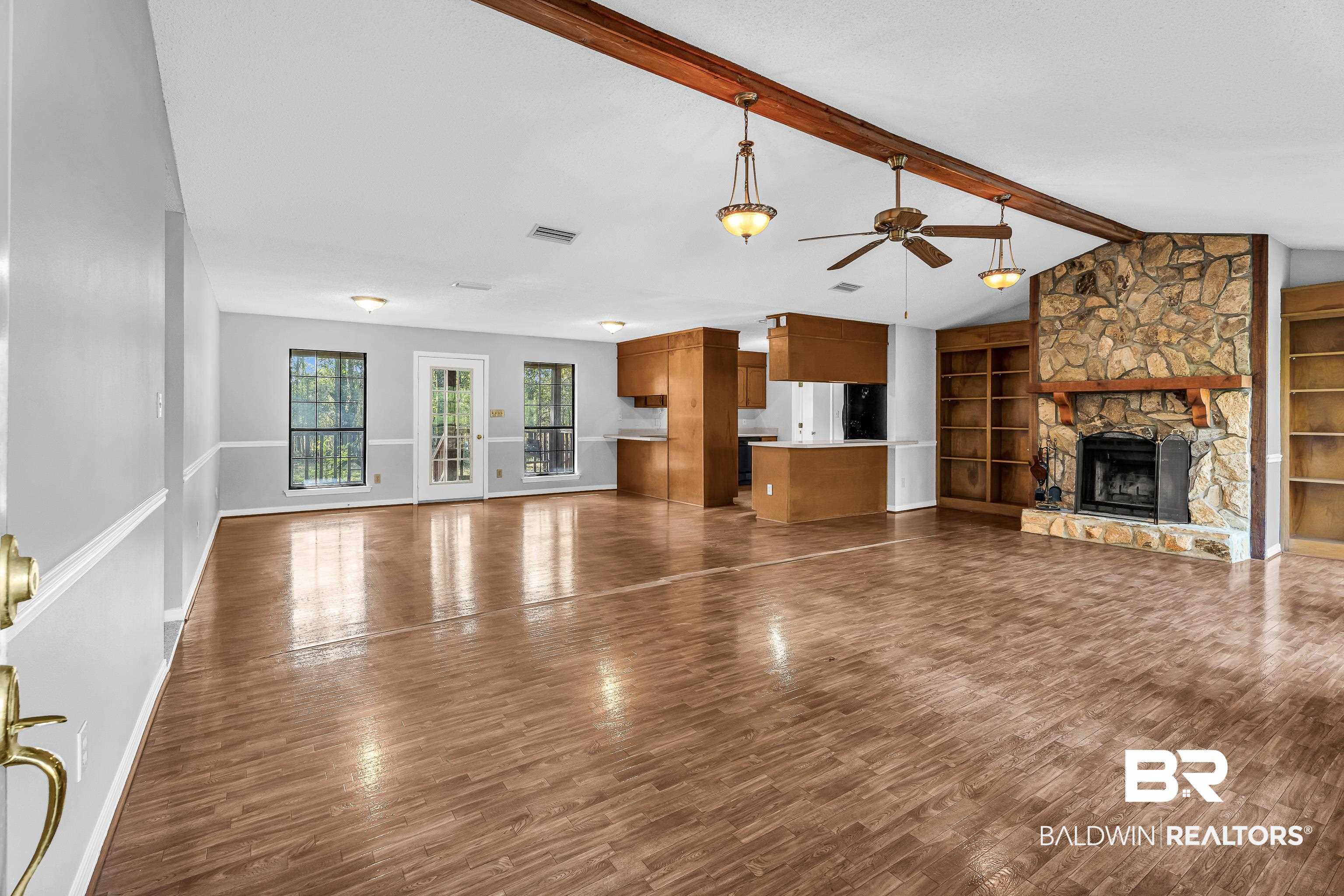 7787 Bellingrath Road Theodore, AL 36582 - Photo 12 of 36 Unfurnished living room featuring built in shelves, a stone fireplace, dark wood-style flooring, and ceiling fan