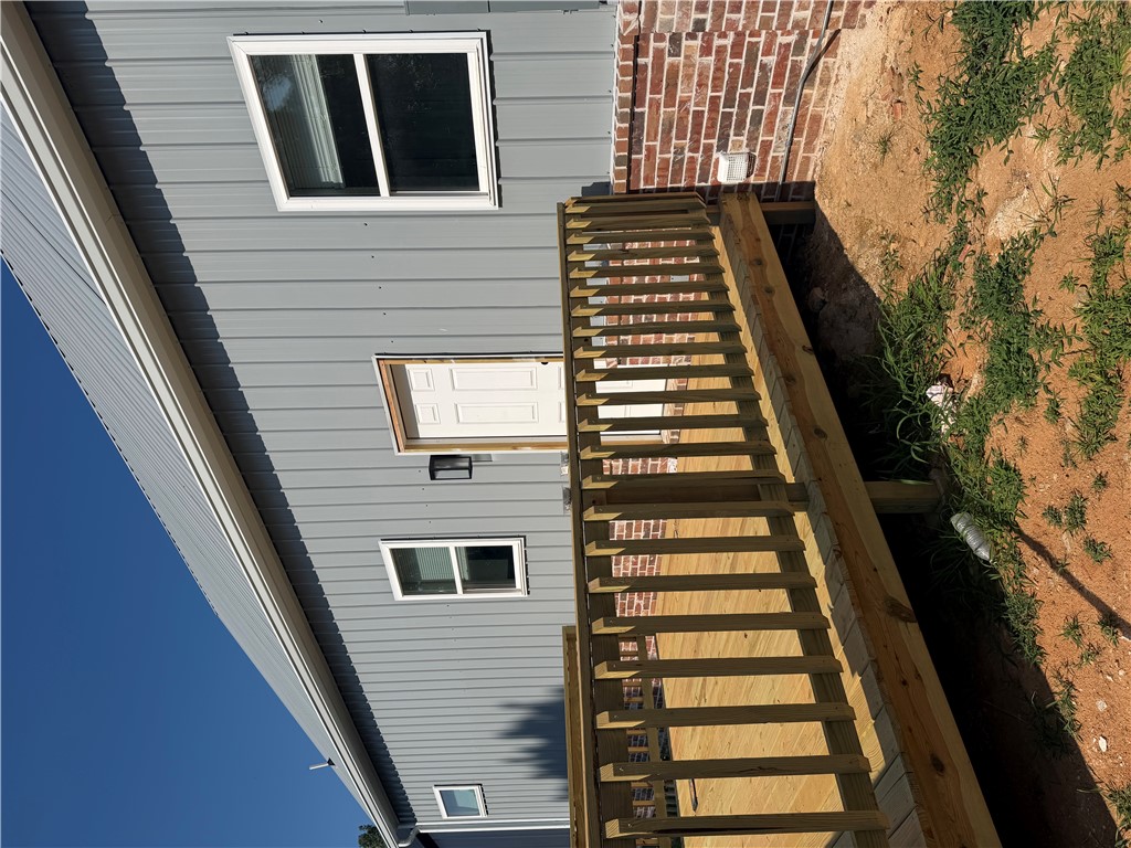Exterior with gray vertical panel siding, a metal roof, and a wood deck