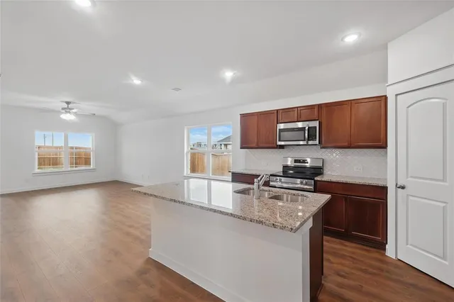 a kitchen with stainless steel appliances granite countertop a sink dishwasher and a stove with wooden floor