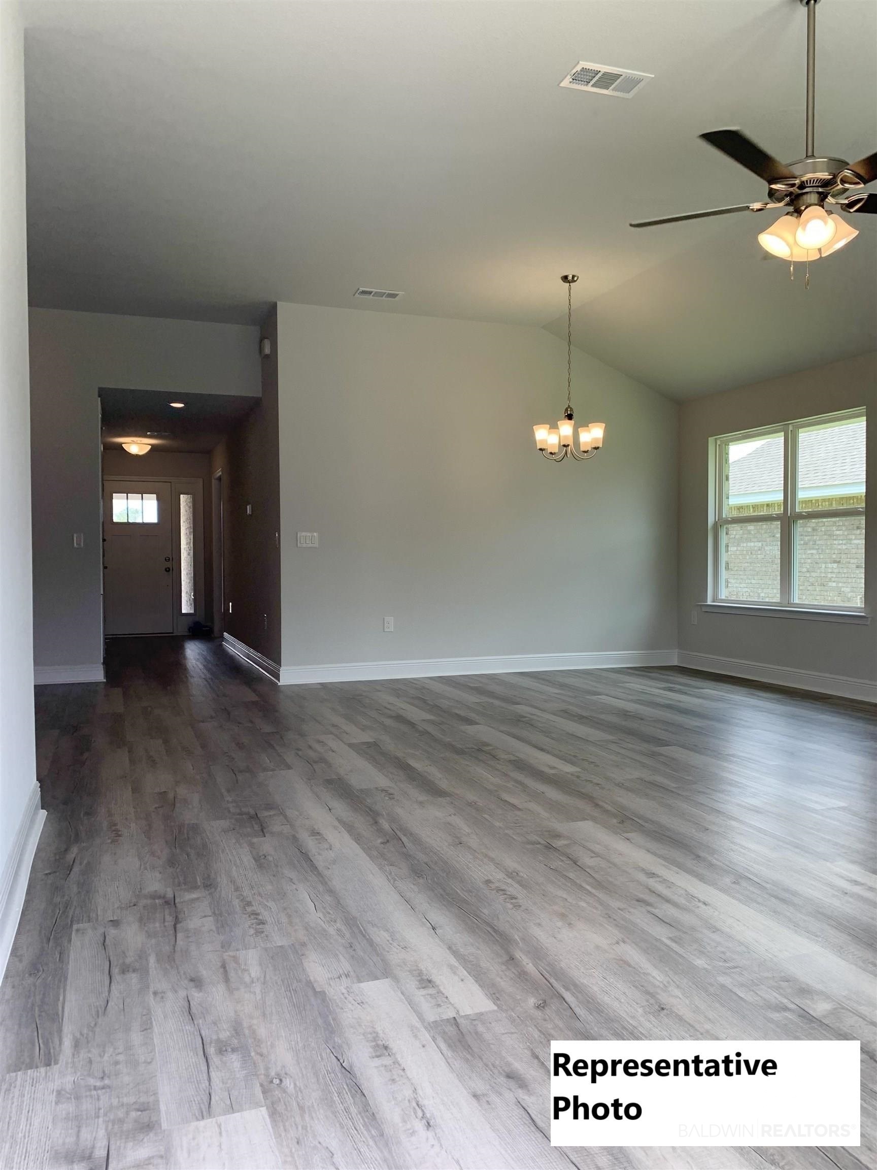 645 Revere Street Foley, AL 36535 - Photo 4 of 14 Spare room with hardwood / wood-style floors, lofted ceiling, and ceiling fan with notable chandelier