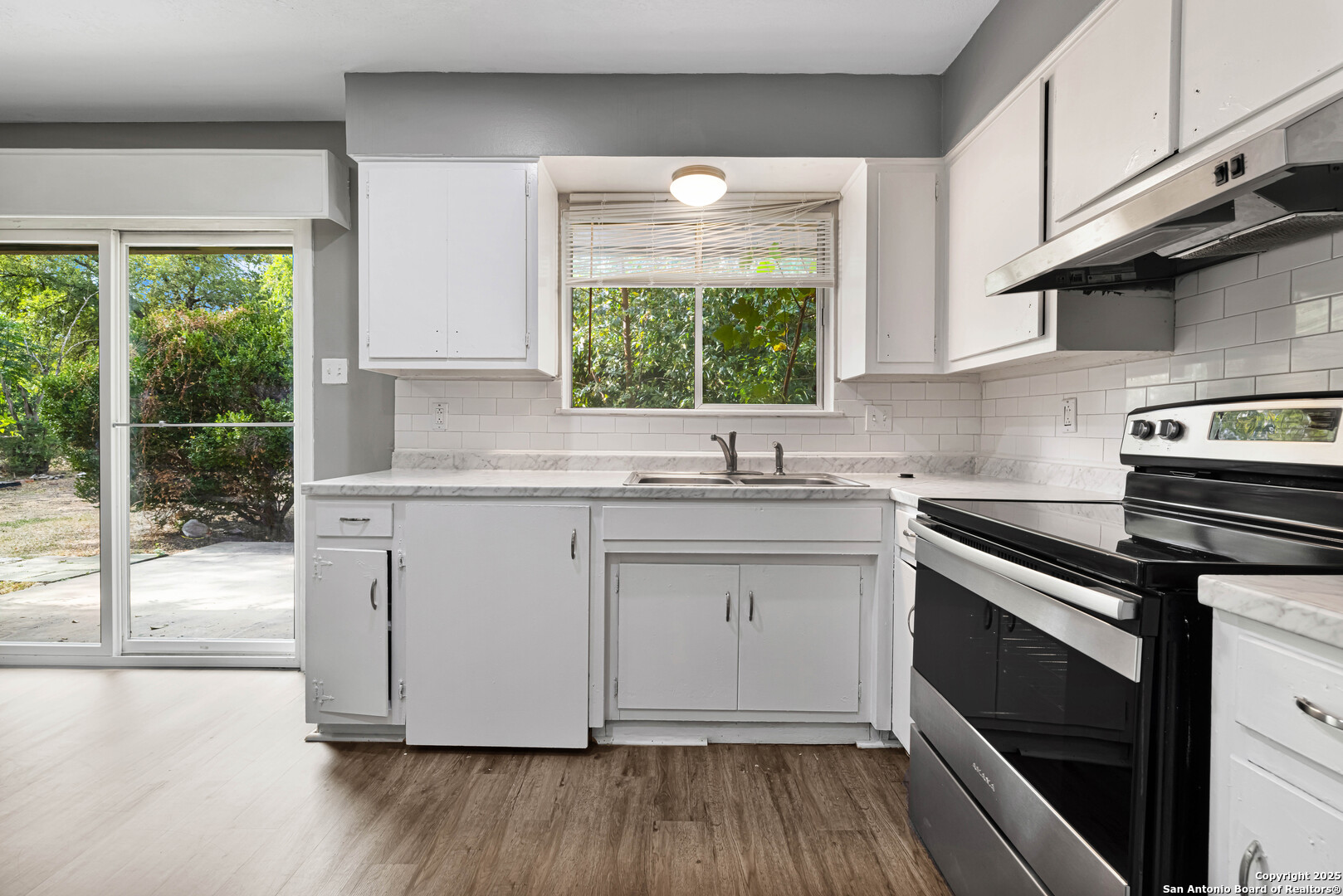 6012 Evers Road Leon Valley, TX 78238 - Photo 14 of 17 a kitchen with appliances cabinets a large window and a sink