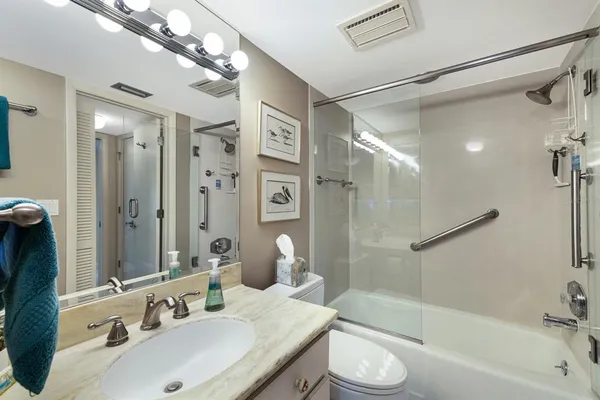 a bathroom with a bathtub shower sink vanity and toilet