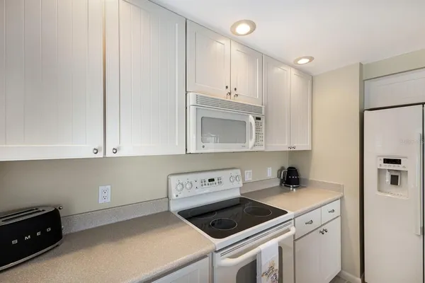 a kitchen with white cabinets and white appliances