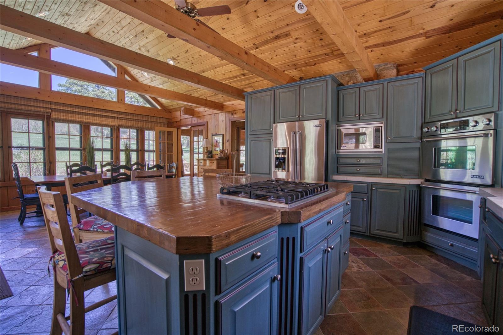 8555 Cuerna Verde Road Rye, CO 81069 - Photo 4 of 35 a kitchen with stainless steel appliances granite countertop a stove a refrigerator a sink a dining table and chairs with wooden floor
