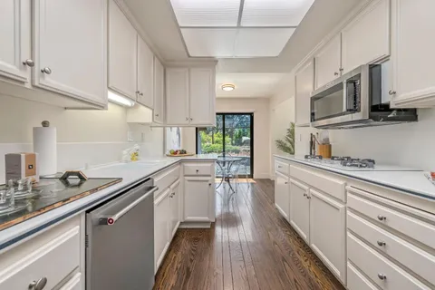 a kitchen with stainless steel appliances white cabinets sink and wooden floor