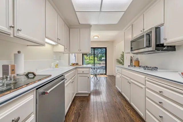 a kitchen with stainless steel appliances white cabinets sink and wooden floor
