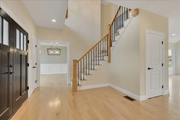 a view of an entryway with wooden floor leading to a furnished livingroom and windows