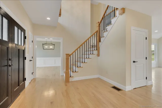 a view of an entryway with wooden floor leading to a furnished livingroom and windows