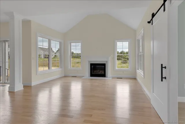 an empty room with wooden floor fireplace and windows