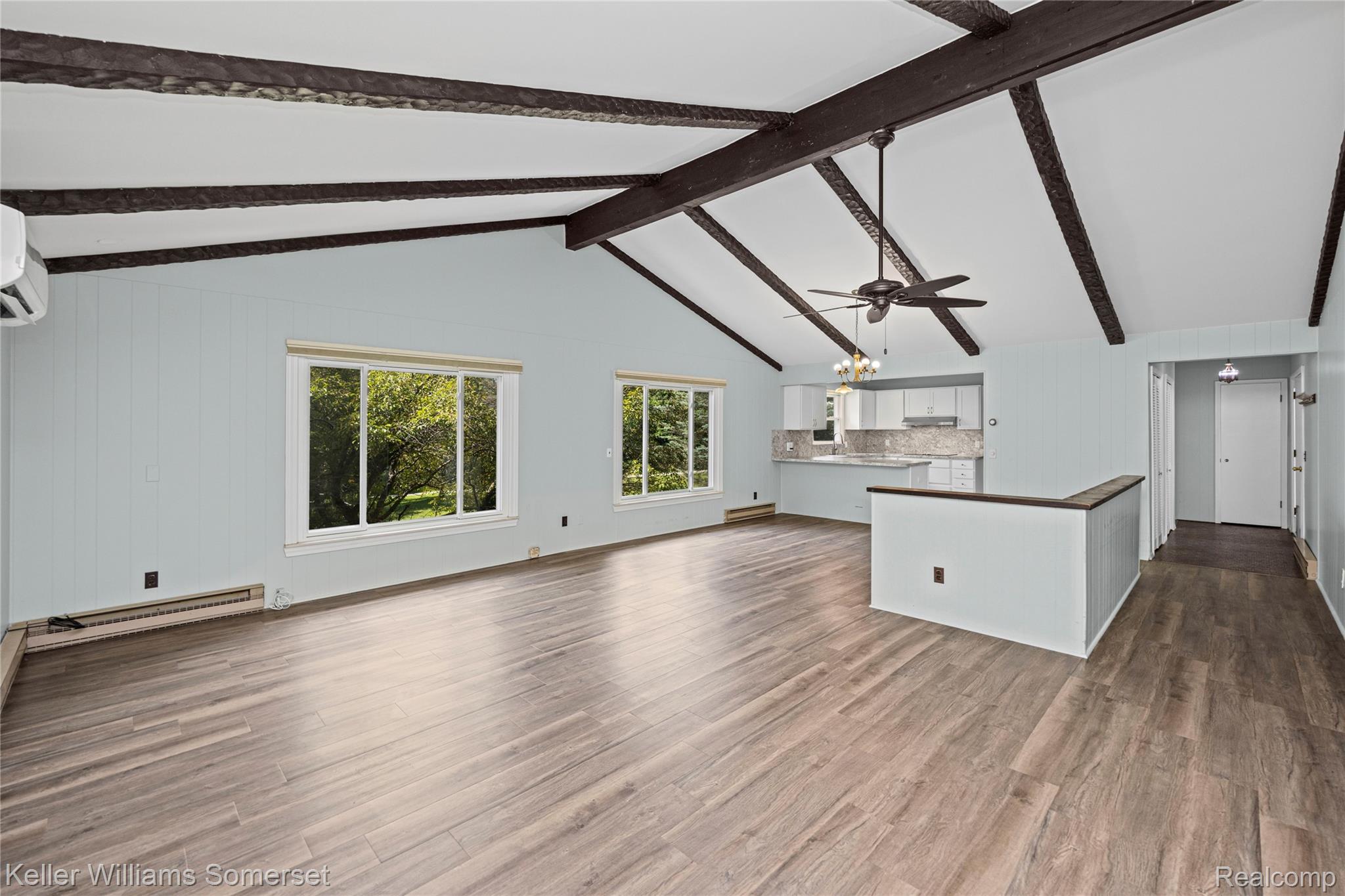 2344 Rochester Road Leonard, MI 48367 - Photo 11 of 66 Vaulted ceilings with exposed beams define this room, featuring wood-finish flooring and light blue wall panels
