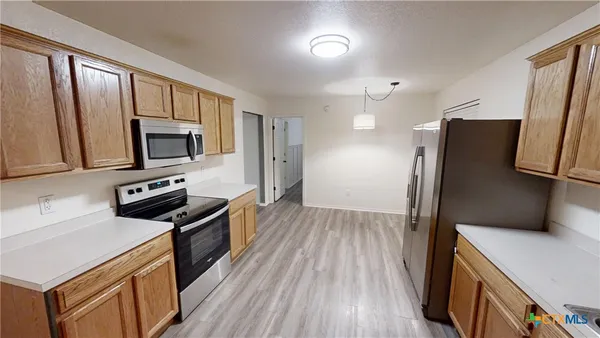 a kitchen with granite countertop a refrigerator stove and microwave