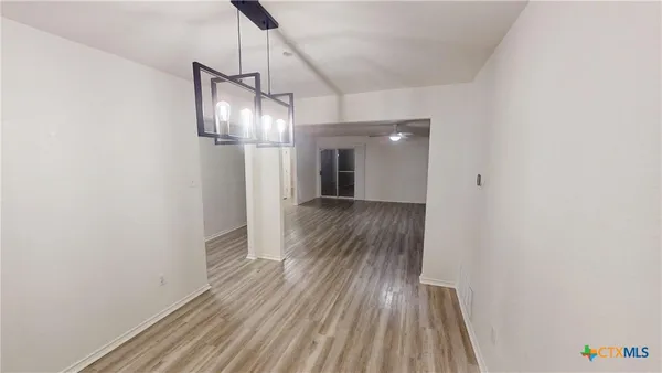 a view of a hallway with wooden floor and chandelier