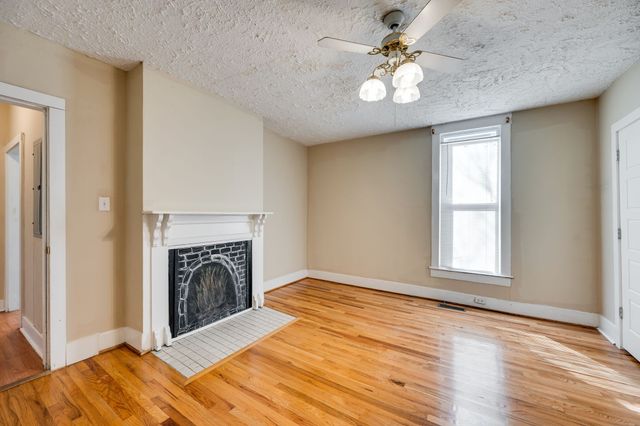 an empty room with windows fireplace and a ceiling fan