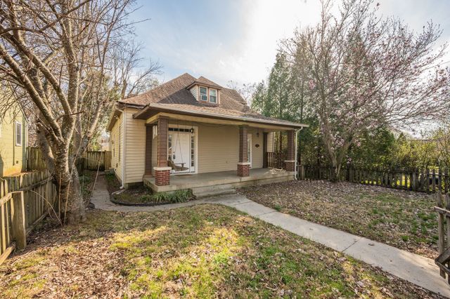 a view of a house with a yard and large tree