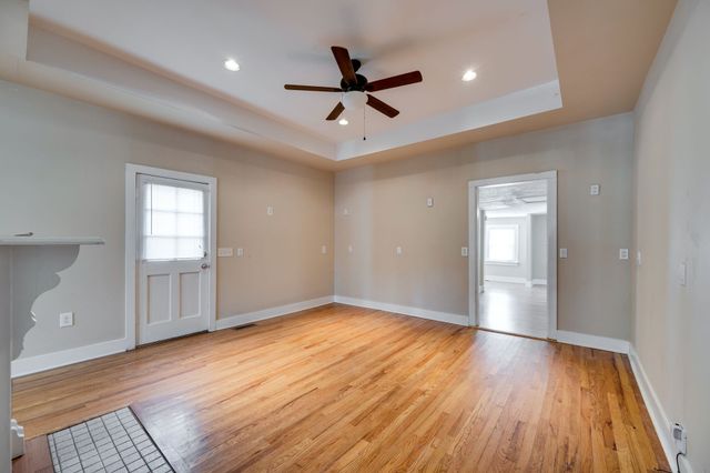 a view of empty room with wooden floor and ceiling fan