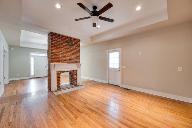 an empty room with windows fireplace and a ceiling fan